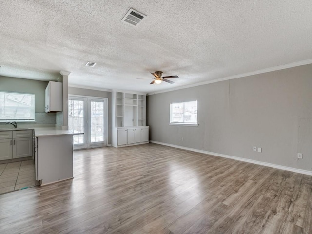 unfurnished living room featuring light wood finished floors, visible vents, and a wealth of natural light