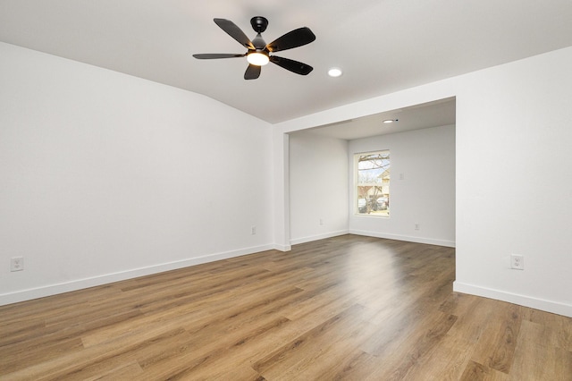 empty room with baseboards, lofted ceiling, ceiling fan, light wood-type flooring, and recessed lighting