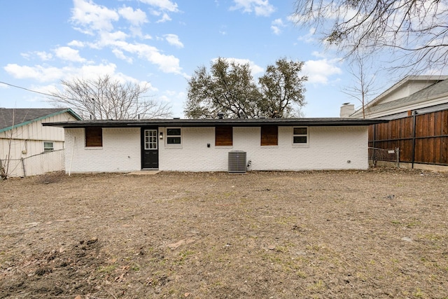 back of house with central AC, fence, and brick siding