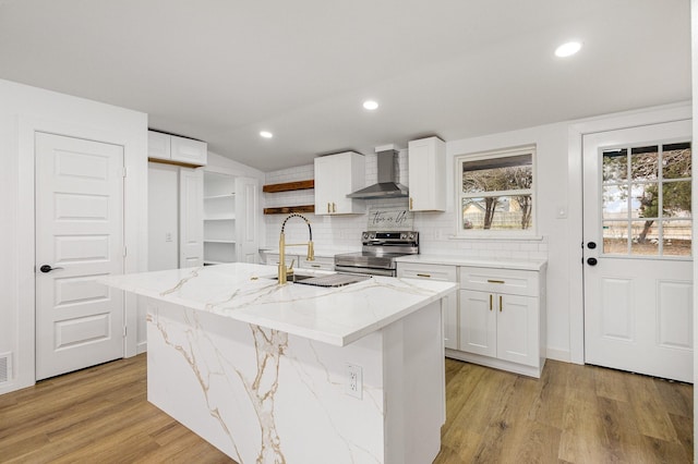 kitchen with open shelves, white cabinets, stainless steel range with electric cooktop, a sink, and wall chimney range hood