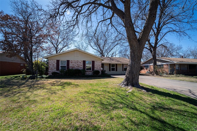 view of front of home with driveway, a front yard, and brick siding