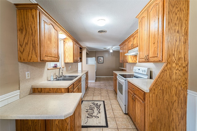 kitchen featuring visible vents, light tile patterned flooring, a sink, white appliances, and under cabinet range hood