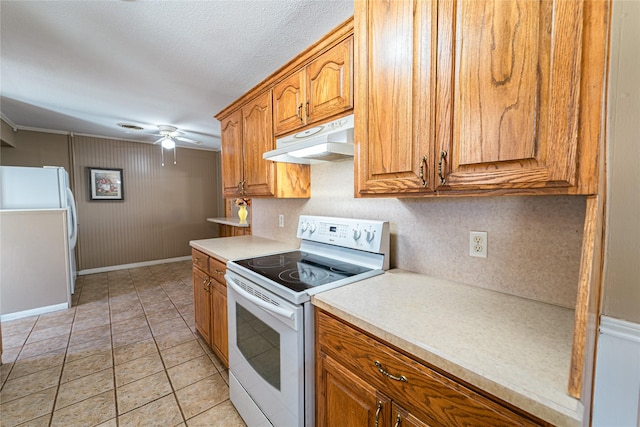 kitchen with white appliances, brown cabinetry, a ceiling fan, light countertops, and under cabinet range hood