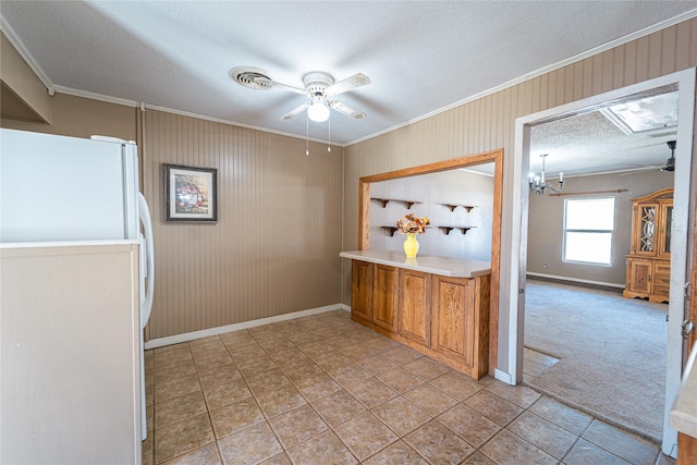 kitchen with brown cabinets, crown molding, freestanding refrigerator, ceiling fan, and a textured ceiling