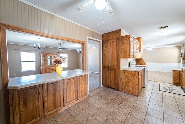 kitchen featuring visible vents, ornamental molding, brown cabinets, white electric range, and ceiling fan with notable chandelier