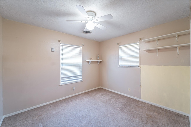 carpeted spare room featuring baseboards, a textured ceiling, visible vents, and a ceiling fan