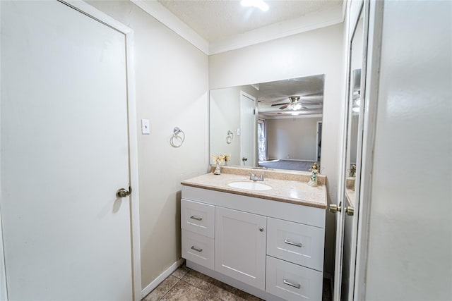 bathroom with tile patterned flooring, a textured ceiling, crown molding, and vanity