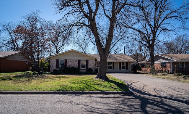 ranch-style home with driveway, a front yard, and brick siding