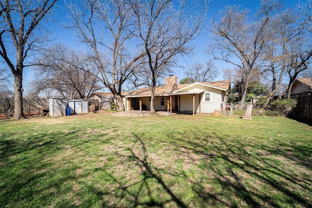 view of yard featuring a shed, a fenced backyard, and an outbuilding