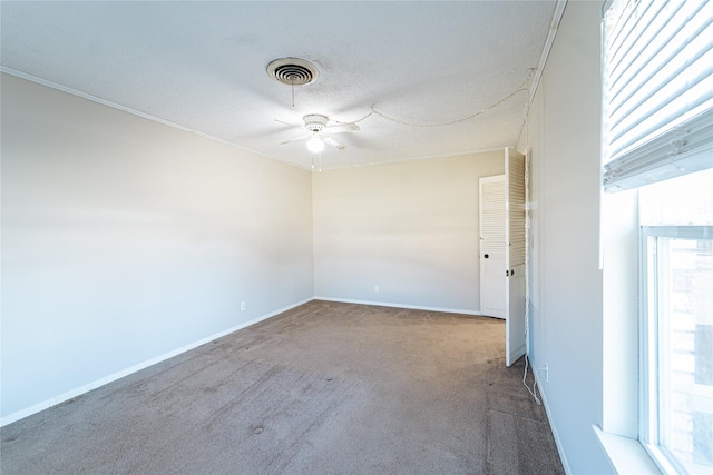 unfurnished room with visible vents, plenty of natural light, a textured ceiling, and carpet flooring