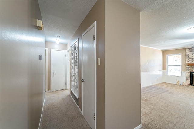 hallway featuring a textured ceiling, a wainscoted wall, and carpet