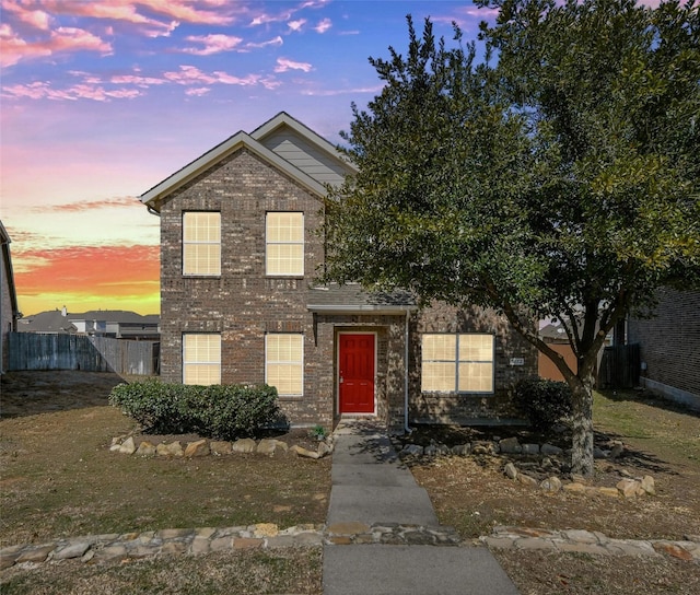 traditional home featuring brick siding and fence