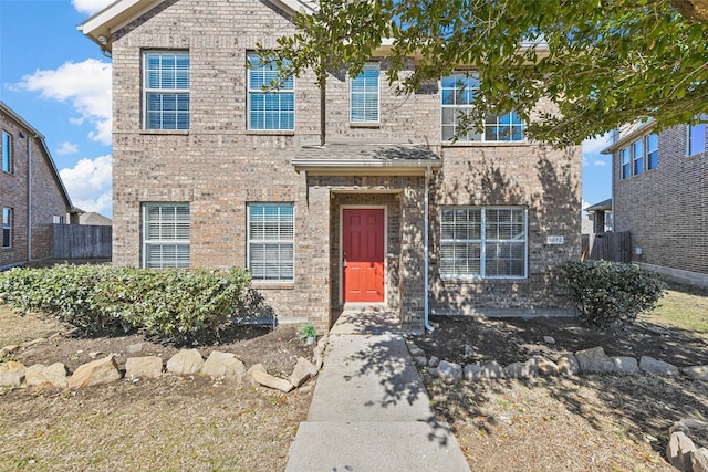 view of front of home featuring brick siding and fence