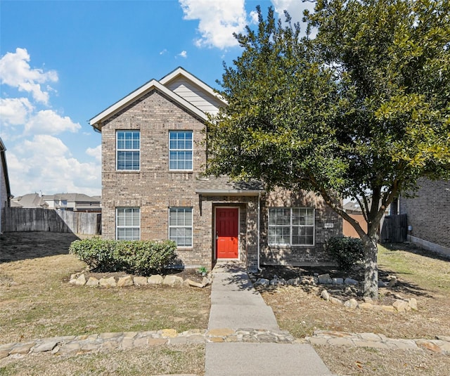 traditional-style house featuring brick siding, a front lawn, and fence