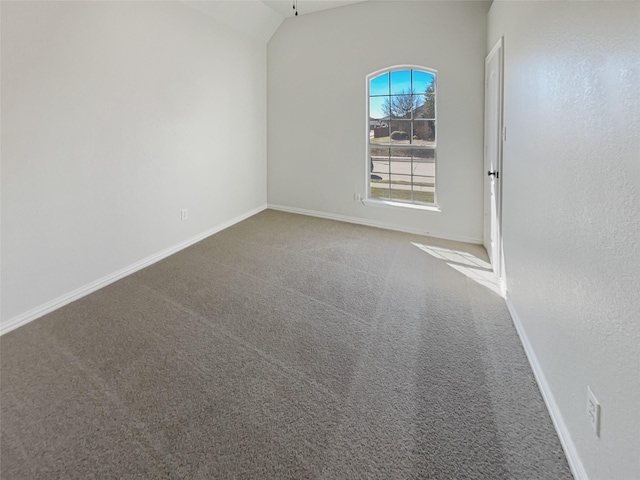 carpeted spare room with lofted ceiling and baseboards