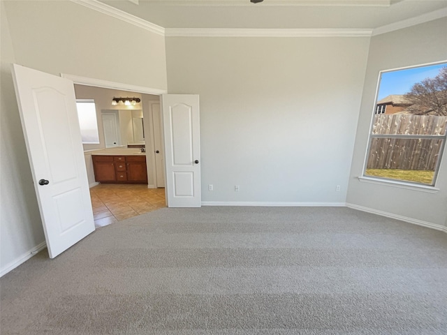 unfurnished bedroom with light colored carpet, crown molding, and baseboards