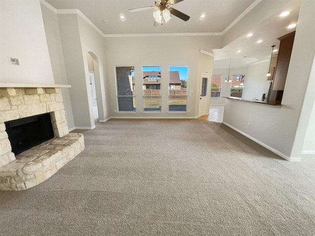 unfurnished living room with light carpet, baseboards, crown molding, and a stone fireplace