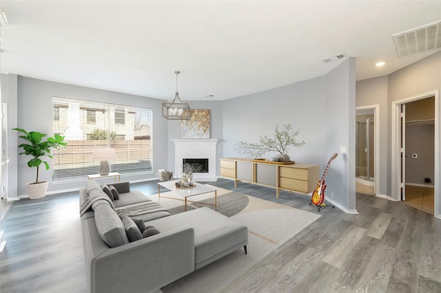 living area featuring a fireplace, wood finished floors, visible vents, and baseboards