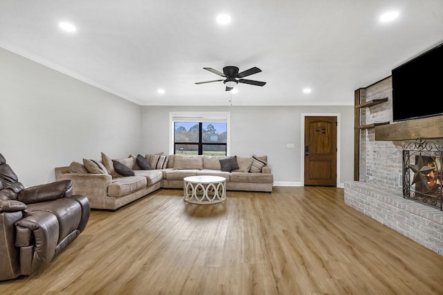 living room featuring crown molding, recessed lighting, a brick fireplace, and light wood-style floors