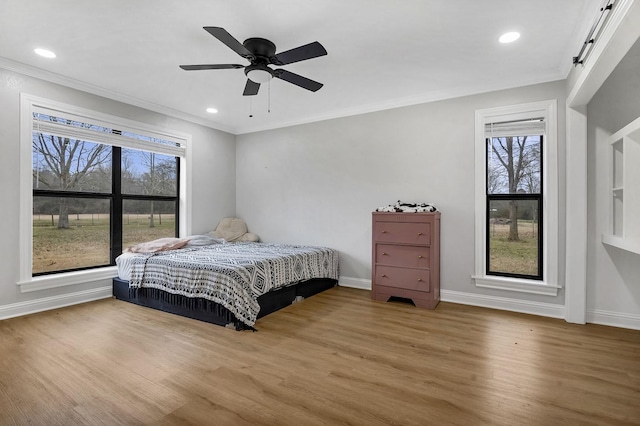 bedroom with a barn door, multiple windows, ornamental molding, and wood finished floors