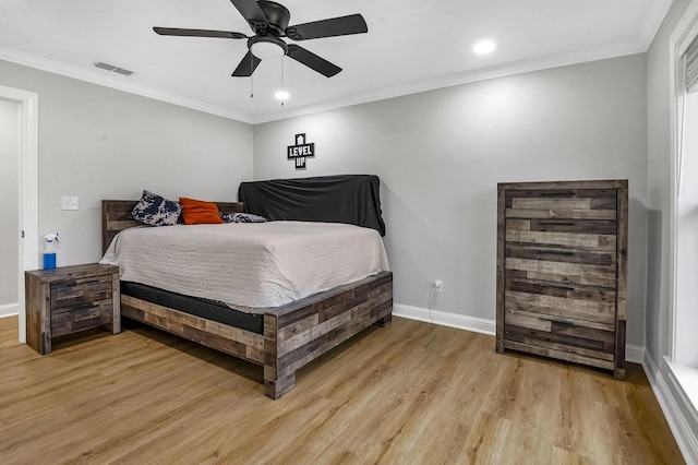 bedroom with visible vents, baseboards, light wood-style flooring, ceiling fan, and ornamental molding