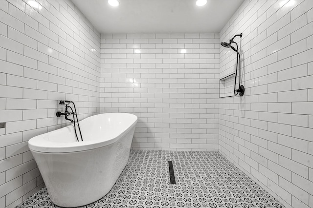 bathroom featuring a soaking tub, tile walls, and tiled shower