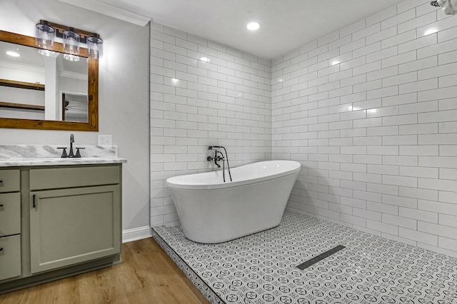 full bathroom featuring a freestanding tub, recessed lighting, wood finished floors, vanity, and tile walls