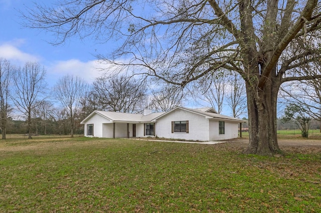 view of front of home with a front lawn, a chimney, and brick siding