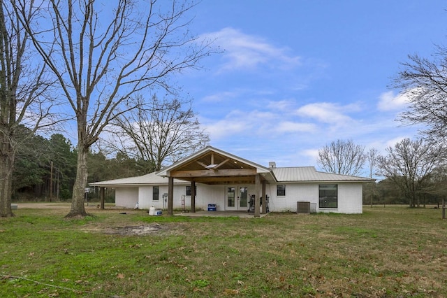 back of house featuring metal roof, a yard, and central AC unit