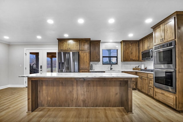 kitchen featuring stainless steel appliances, a sink, light countertops, a center island, and tasteful backsplash