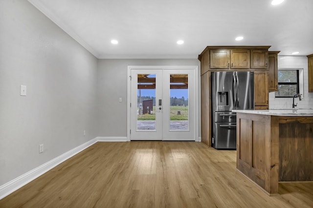 kitchen with tasteful backsplash, stainless steel fridge, baseboards, light countertops, and light wood-style floors