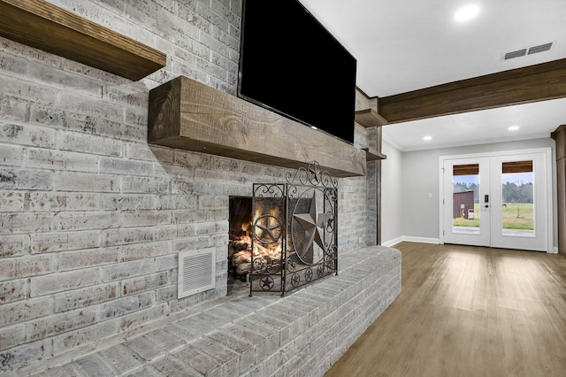 unfurnished living room featuring french doors, visible vents, a fireplace, and wood finished floors