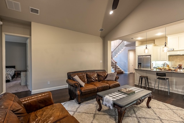 living area with dark wood-style flooring, stairway, and visible vents