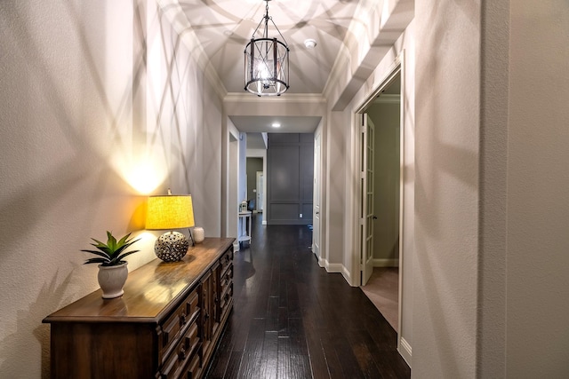 hall featuring a textured wall, a notable chandelier, baseboards, dark wood-style floors, and crown molding