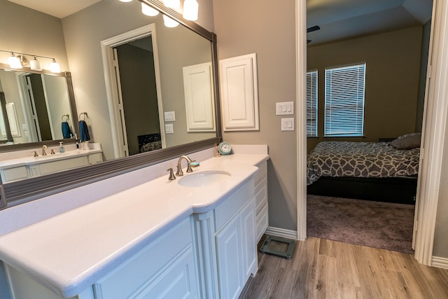 full bathroom with ensuite bathroom, wood finished floors, vanity, and baseboards