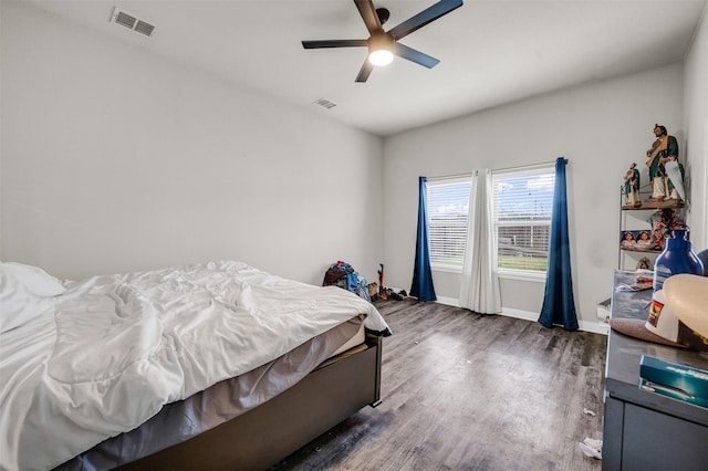 bedroom with dark wood-type flooring, a ceiling fan, visible vents, and baseboards