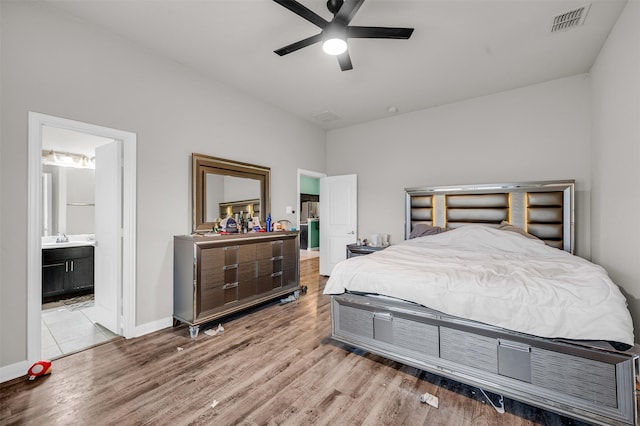 bedroom with light wood finished floors, visible vents, connected bathroom, ceiling fan, and baseboards