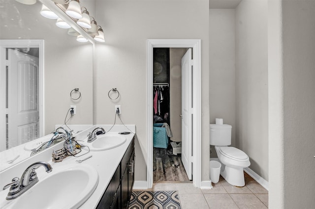 bathroom featuring double vanity, a sink, toilet, and tile patterned floors