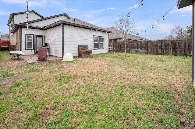 rear view of house with a yard, a fenced backyard, and a patio