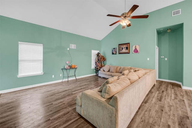 living room with high vaulted ceiling, wood finished floors, visible vents, and baseboards