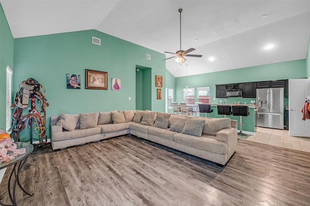 living room with light wood-style floors, visible vents, vaulted ceiling, and a ceiling fan