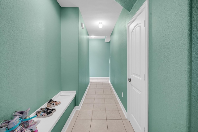 corridor with light tile patterned floors and baseboards