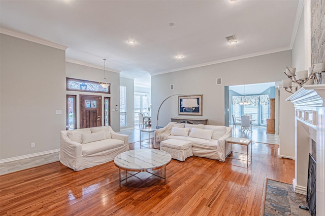 living room with light wood-style flooring, a fireplace, crown molding, and a wealth of natural light