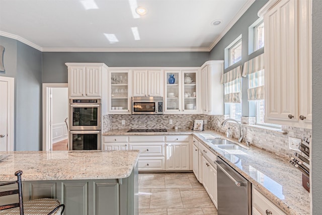 kitchen featuring light stone counters, a breakfast bar area, stainless steel appliances, glass insert cabinets, and a sink