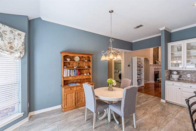 dining area featuring a fireplace, visible vents, baseboards, ornamental molding, and washer / clothes dryer