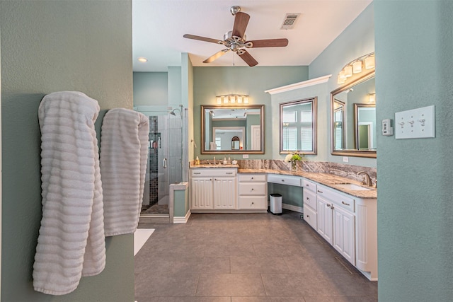 bathroom featuring visible vents, a sink, a shower stall, and double vanity