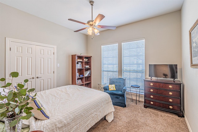 bedroom with a closet, light carpet, ceiling fan, and baseboards