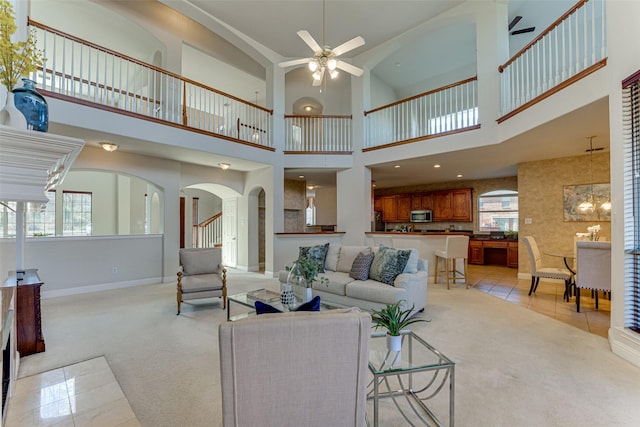 living room featuring light carpet, light tile patterned floors, baseboards, and ceiling fan with notable chandelier