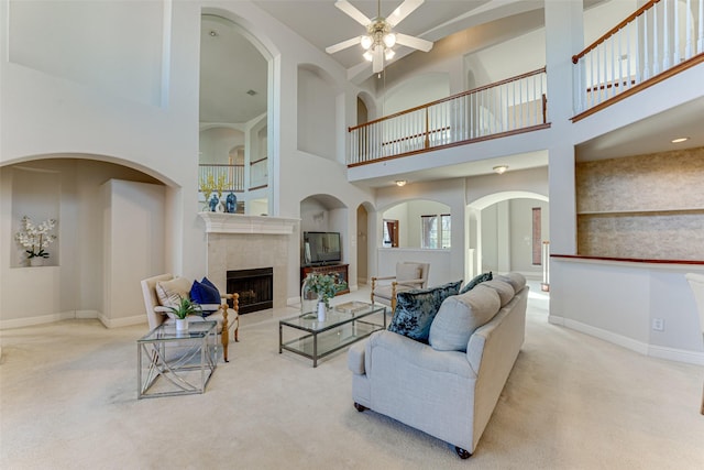 living area with baseboards, light colored carpet, and a tiled fireplace