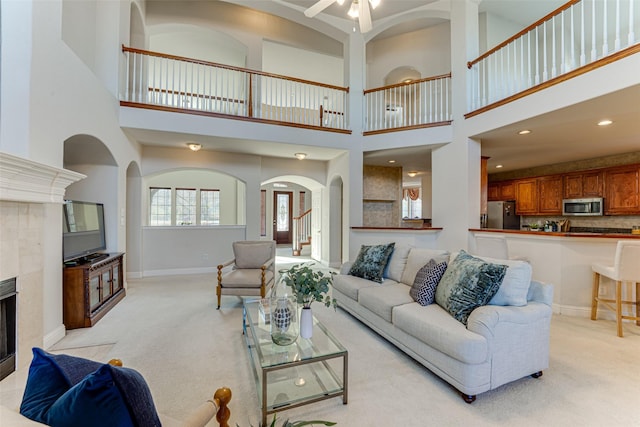 living room with ceiling fan, recessed lighting, light colored carpet, a fireplace, and baseboards